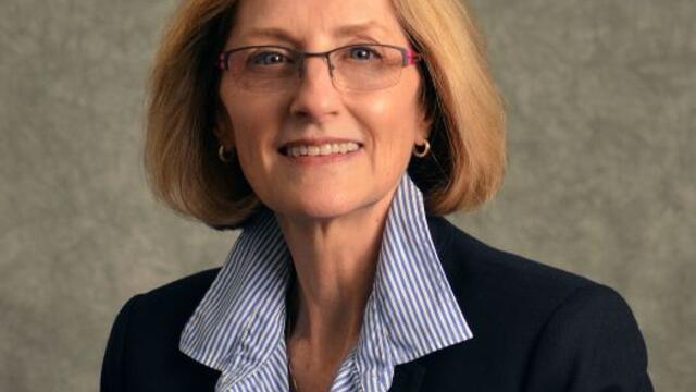 image of Holly Mayer, wearing glasses, in a blue shirt and black blazer