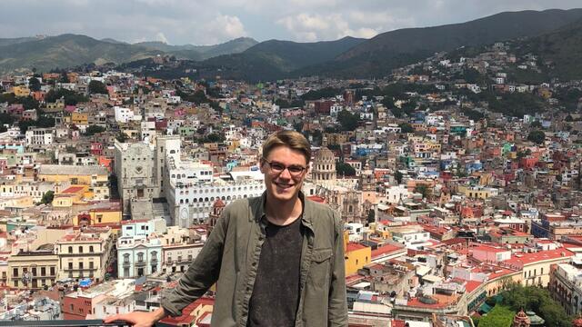 Alex Voisine standing in front of a cityscape.