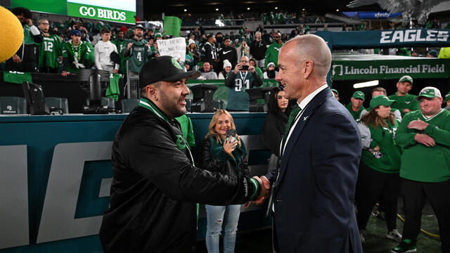 Image of Temple alum greeting Philadelphia Eagles president inside a stadium.