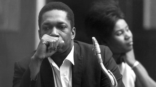 Coltrane sitting with his saxophone.