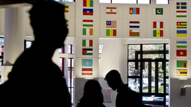 Students silhouetted against the global flags in the student center