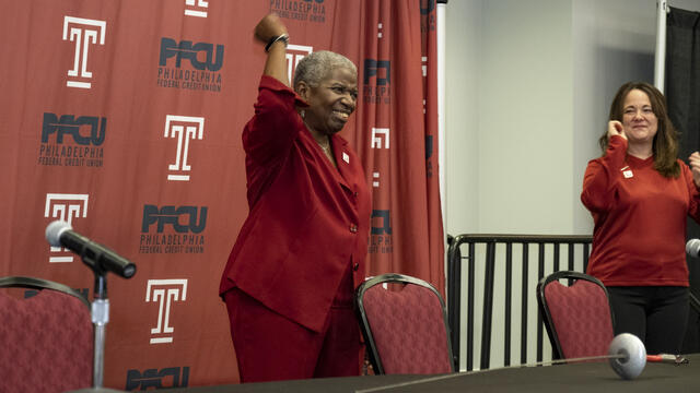 Image of Temple University’s former fencing coach Nikki Franke, wearing a cherry suit and pumping her fist. 
