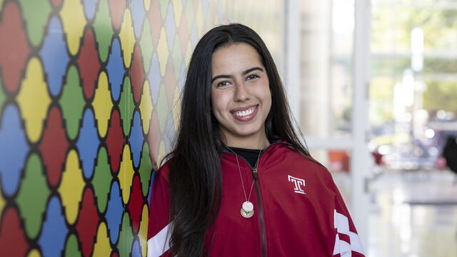 Raphaela leans against a colorful wall in the Art of Bread inside Tyler School of Art
