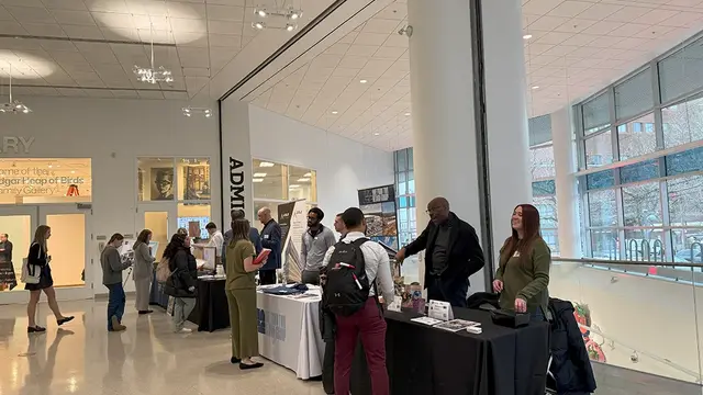 Students walking through the Tyler building lobby and looking at vendor tables at the 2025 AED Career Fair