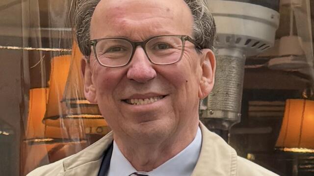 white male wearing glasses, short brow hair, stripe tie, tan jacket