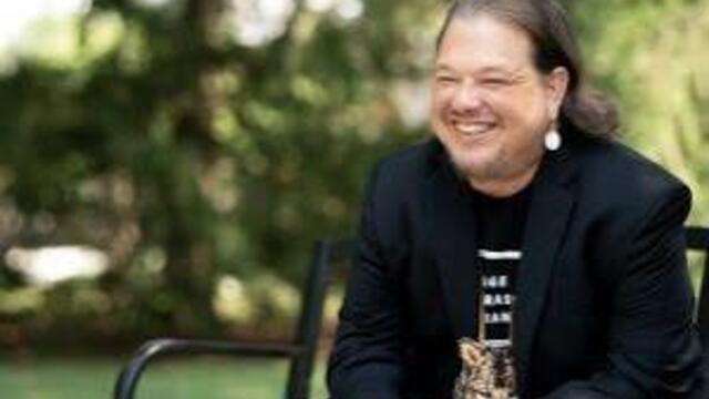 image of Jeremy sitting on a bench smiling into the distance