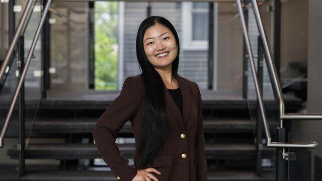 Image of Temple alum standing around a stairwell while wearing a blazer and smiling.
