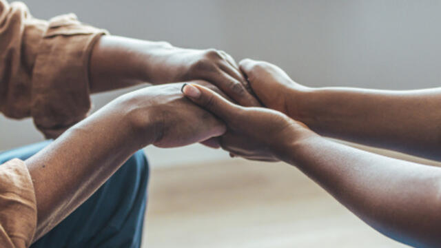 A personal care home administrator holding the hands of a resident.