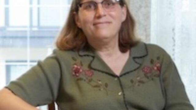 image of Elizabeth in a green shirt wearing glasses smiling at the camera