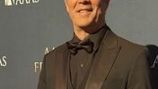 Sergio (Serge) Rey standing in a black suit smiling at the camera