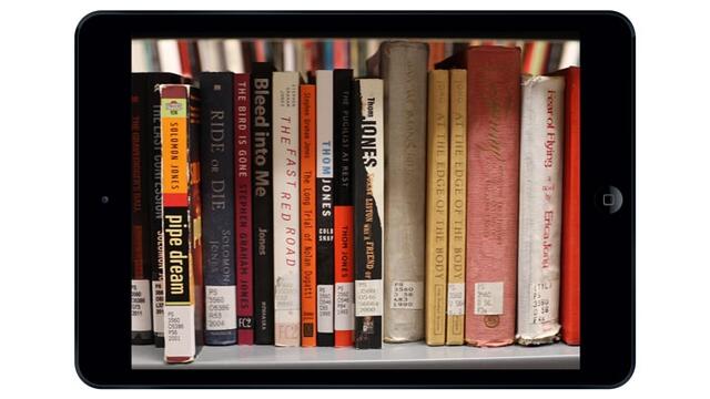 An iPad with a photo of book spines on the screen.