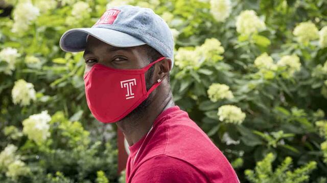 A Temple community member wearing a Temple-branded mask.