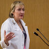 Darilyn Moyer wearing a lab coat and speaking at a podium.