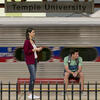 Two students waiting for a train at Temple University s SEPTA Regional Rail Station as a train passes by.