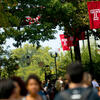 Students walking on campus under Temple T flags.