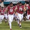 Temple football players running onto field for a game