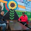 Two men sitting in front of a new colorful mural in North Philadelphia.