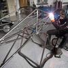A Temple engineering students welds a portion of a race car.