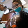 A female patient looking in a handheld mirror at her new dental crown.