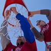 Two male student volunteers hanging a basketball net at Amos Recreation Center.