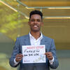 A man in a gray suit holding a sign that reads finance at New York Life.