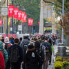 students walking on campus underneath red flags bearing the Temple T .