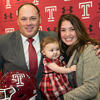Geoff Collins holding a Temple helmet and smiling with wife and baby daughter.