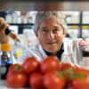 Antonio Giordano holding a pipette, surrounded by tomatoes in a lab