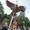 construction workers watch as a bronze owl statue is lowered