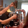 A student barista pouring cold brew coffee