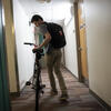 A student rolls his bike down the hallway of a residence hall