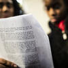 Two Black women read a page from a document together.