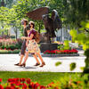 Two students wearing masks walk past an owl statue on Temple's Main Campus.