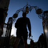 A student in silhouette walks through gates on Temple's Main Campus.