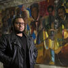 Tyler A. Ray stands in front of one of 14 murals inside the Church of the Advocate.