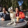 Two students sitting at a table outside with a skeleton