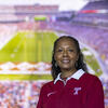 A woman wearing a cherry and white Temple shirt pictured with the background of Lincoln Financial Field.