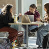 Three students at a table working on laptops