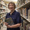 Sandi Thompson standing in the book stacks with a book in her hands at Ambler Campus Library