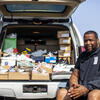 Image of a North Philadelphia resident in front of his truck load of sneakers.