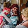 The Mermaid Princess smiles as she hugs a child in a hospital room
