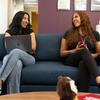 Two Temple students sitting on a couch laughing.