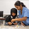 A medical student helps a middle school student perform an activity