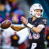 Image of a college athlete wearing a white helmet with a Temple logo and a black, cherry and white jersey, throwing a football.
