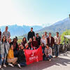 Mountains in the background, a group of Temple students holding a Temple cherry flag.