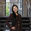Image of Temple alum standing around a stairwell while wearing a blazer and smiling.