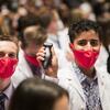 A student displays their new ultrasound device at a white coat ceremony.