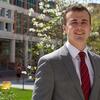 A man in a red tie standing in front of Temple University s Alter Hall.