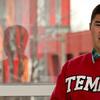 Matthew Velasquez standing in front of a window, wearing a cherry Temple sweatshirt.