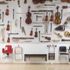 A large display of musical instruments and chairs hanging on a gallery wall.